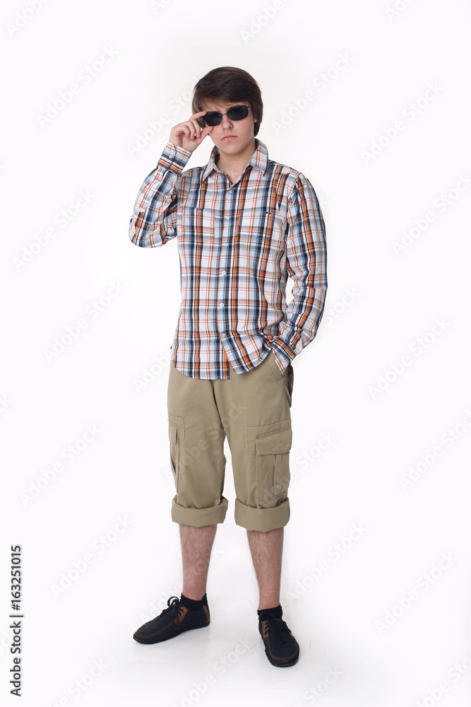 Young fashion man posing in checked shirt and black sunglasses. Handsome guy in street clothes isolated on studio white background. Young fashion man posing in checked shirt and black sunglasses. Handsome guy in street clothes isolated on studio white background.
