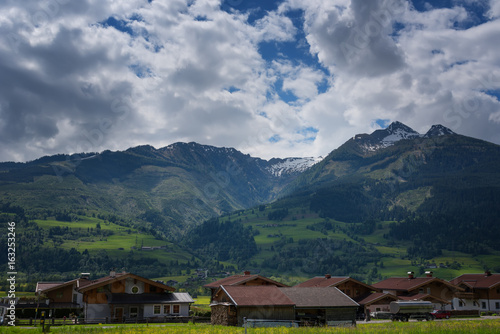 Idyllic landscape in the Alps in springtime with traditional mountain chalet and fresh green mountain pastures with blooming flowers on a beautiful sunny day. Austria, Europe.