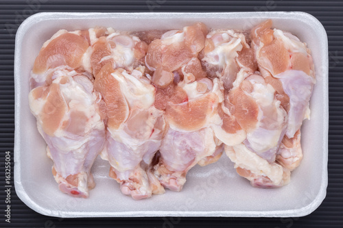 A white foam tray of raw chicken drumsticks from supermarket, fresh food ingredients concept.