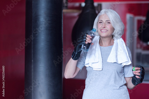 Smiling senior woman drinking water at gym