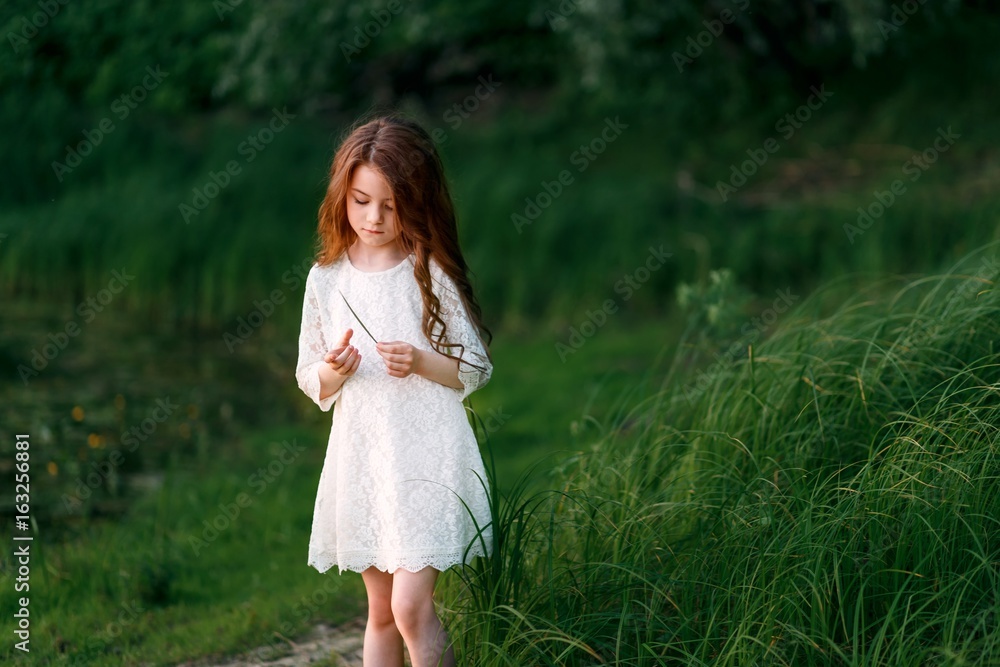 a little girl walking outside in the park at sunset a little girl walking outside in the park at sunset
