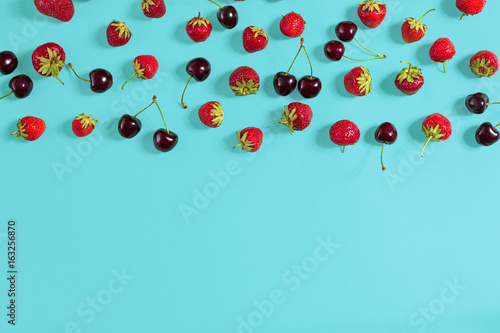 Fresh cherries and strawberries on mint background, top view