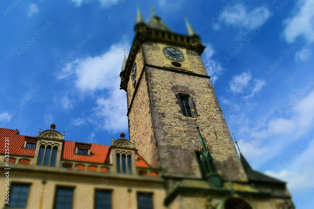 The clock tower of Old Town Hall in Prague in Czech Republic, with blue sky and white clouds in the background. Tilt-shift effect applied.