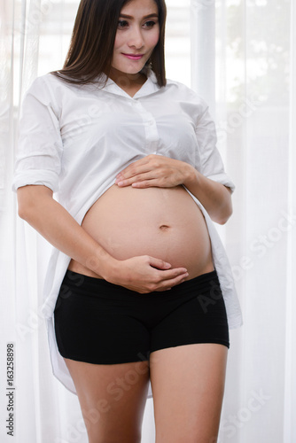Pregnant woman touching stomach by the window. Free Download Pregnant woman touching stomach by the window. - GFXLoad