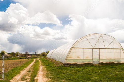 Polythene tunnel as a plastic greenhouse in an allotment with growing vegetables and fruits