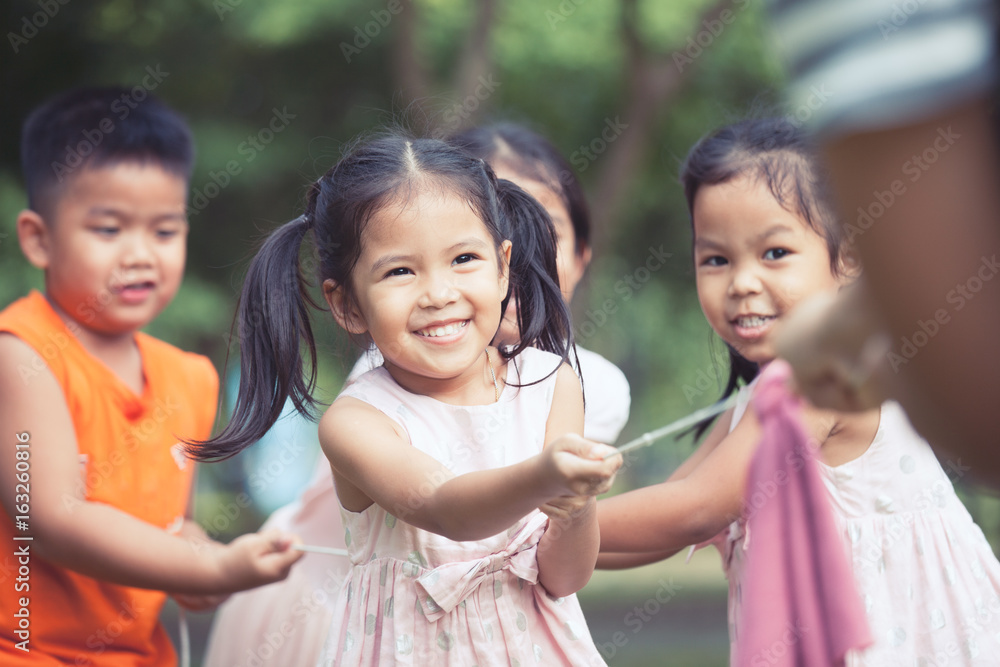 Asian children having fun to play tug-of-war with rope together in the park in vintage color tone Asian children having fun to play tug-of-war with rope together in the park in vintage color tone