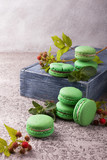 Fresh green mint raspberry french macarons on wooden box and light gray cement table. Close up, copy space, selective focus. 