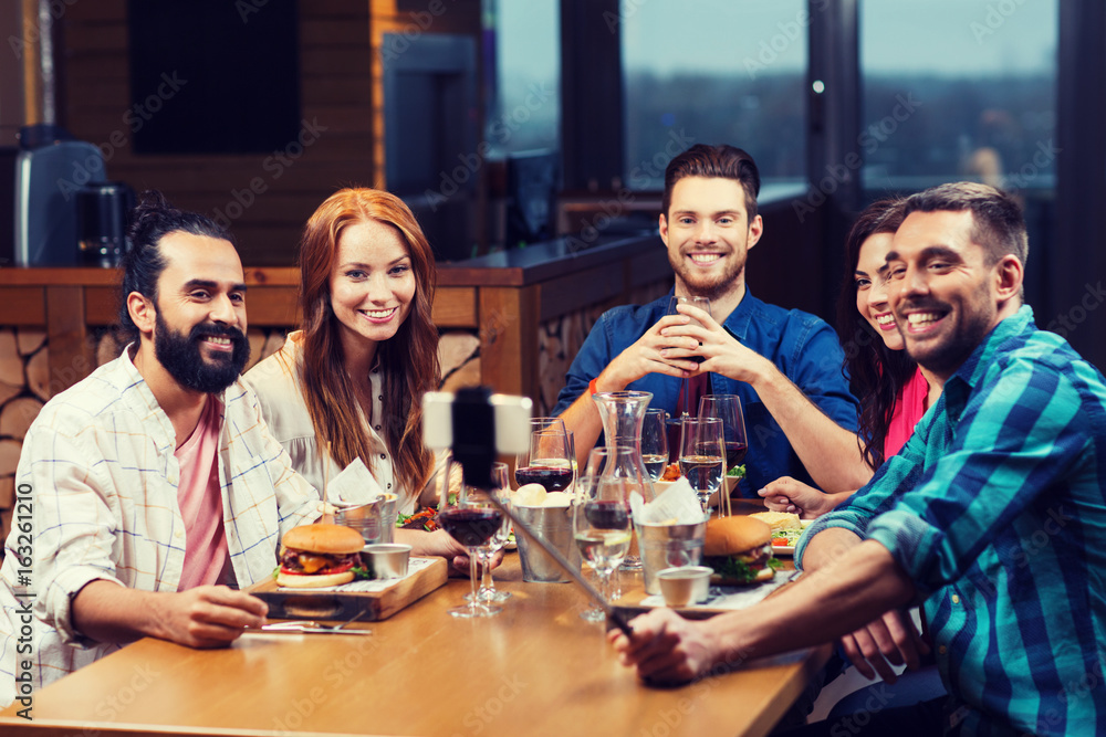 friends taking selfie by smartphone at restaurant friends taking selfie by smartphone at restaurant