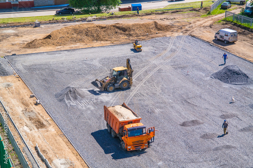 The construction of the school stadium. Excavator, dumper, roller