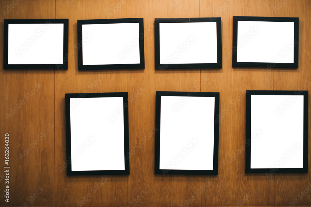 Many black frames with white background hang on wooden walls in the restaurant. Many black frames with white background hang on wooden walls in the restaurant.