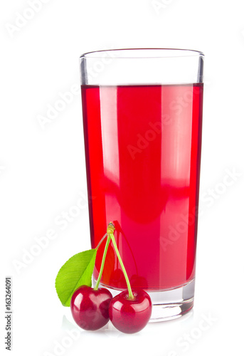 Glass juice and two ripe juicy cherries with green leaf.