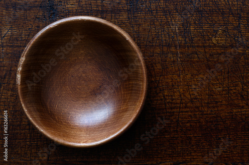 Принти на полотні Empty dark wooden bowl isolated on dark brown wood from above.