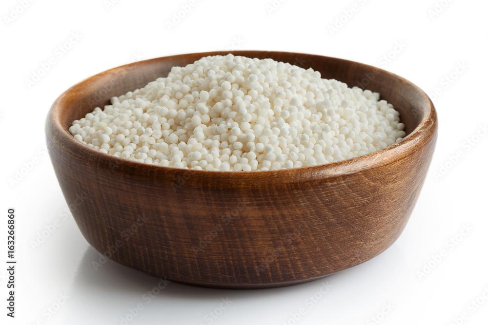 Dry tapioca pearls in dark wooden bowl isolated on white. Dry tapioca pearls in dark wooden bowl isolated on white.