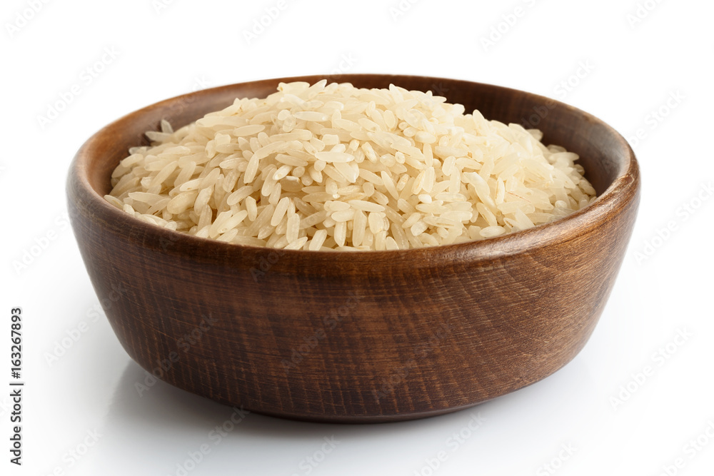 Uncooked long grain white rice in dark wooden bowl isolated on white. Uncooked long grain white rice in dark wooden bowl isolated on white.