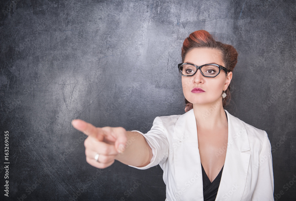 Serious teacher pointing out on chalkboard background Serious teacher pointing out on chalkboard background