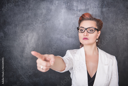 Serious teacher pointing out on chalkboard background