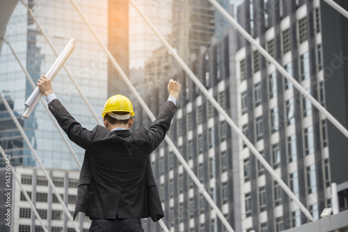 Картината върху платно Professional Construction engineer Manager wear safety yellow helmet holding Blueprint feeling success after complete building project with better structures