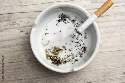 Lit cigarette burning in ashtray close up