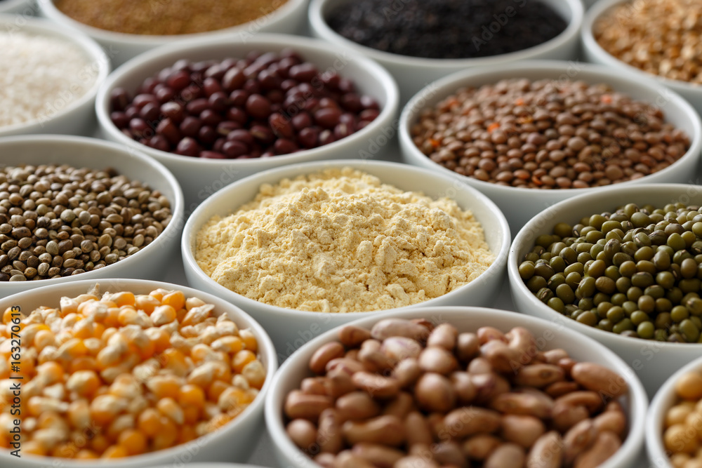 Arranged white bowls with uncooked pulses, grains and seeds on white wood. Arranged white bowls with uncooked pulses, grains and seeds on white wood.