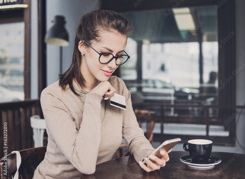 Young woman holding credit card and using smart phone. Online shopping concept Young woman holding credit card and using smart phone. Online shopping concept