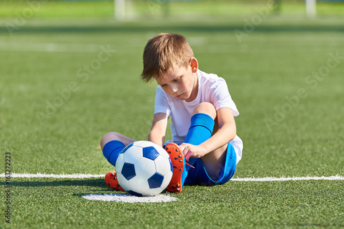 Boy football soccer tying laces him boots on grass © Sergey Ryzhov