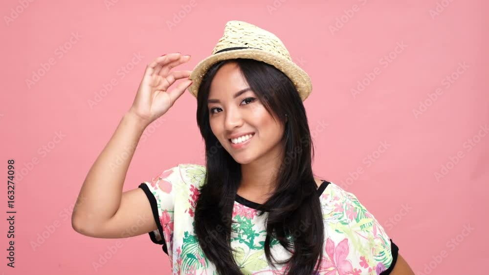 Young beautiful asian woman wearing hat wink over pink background Young beautiful asian woman wearing hat wink over pink background