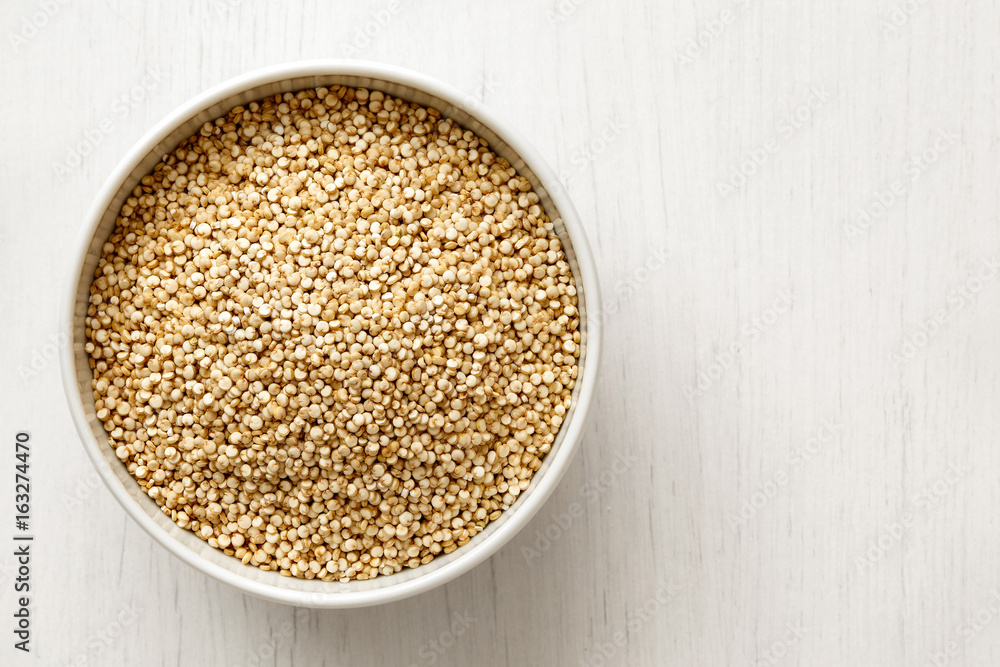 Quinoa seeds in white ceramic dish isolated on painted white wood from above. Quinoa seeds in white ceramic dish isolated on painted white wood from above.