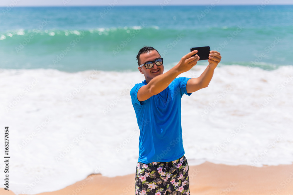 Happy handsome smiling man on vacation laughing at the beach taking selfie Happy handsome smiling man on vacation laughing at the beach taking selfie