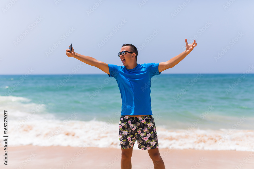 Young man hold cellphone take picture of summer beach panoramic sea view Young man hold cellphone take picture of summer beach panoramic sea view