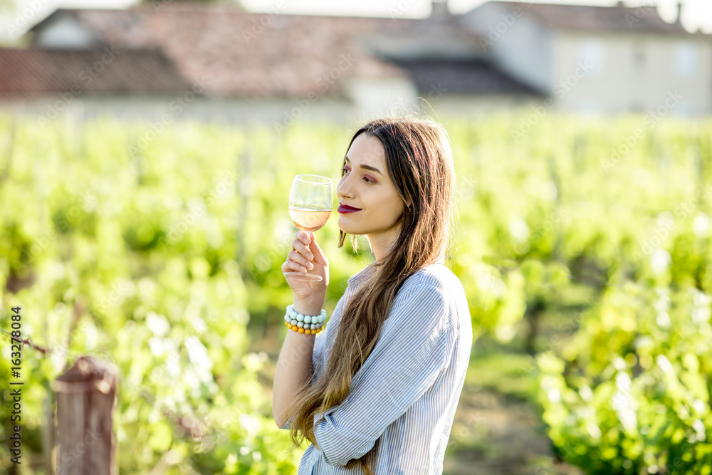 Young woman tasting wine standing outdoors on the vineyard in Bordeaux region during the sunset in France Young woman tasting wine standing outdoors on the vineyard in Bordeaux region during the sunset in France