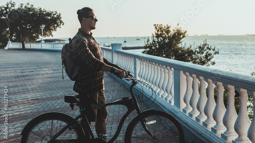 Fototapeta Naklejka Na Ścianę i Meble -  Cyclist Young Man With Bicycle Looking At Sea In Summer Holiday Vacation Traveling Relaxation Concept