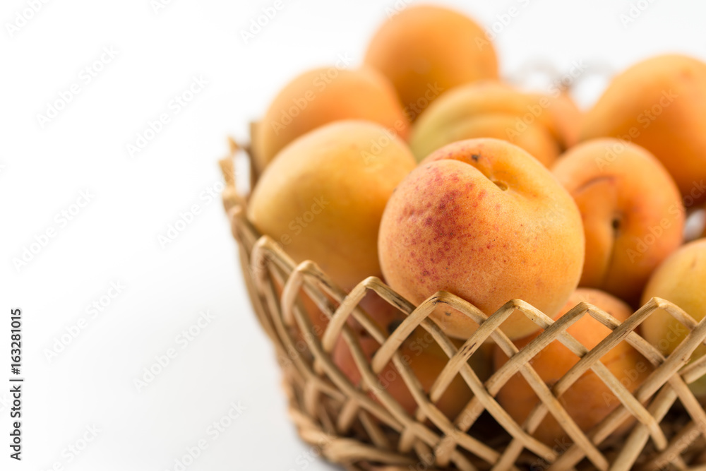 Fresh apricot in the wicker bowl above white background. Fresh apricot in the wicker bowl above white background.