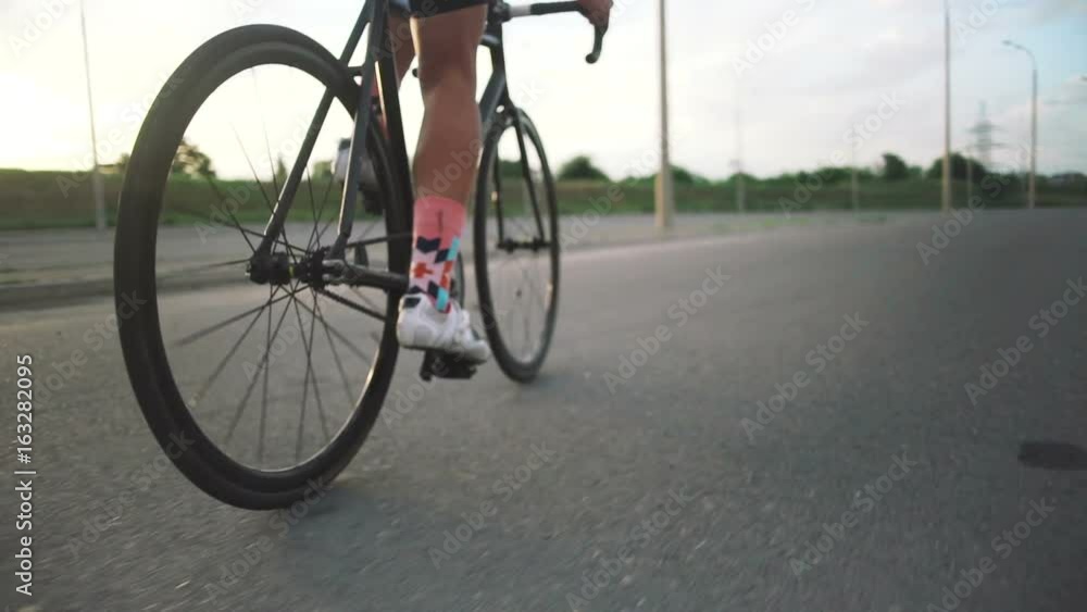 Young handsome hipster man riding fixed gear bicycle during sunset, outdoor. tracking shot Young handsome hipster man riding fixed gear bicycle during sunset, outdoor. tracking shot