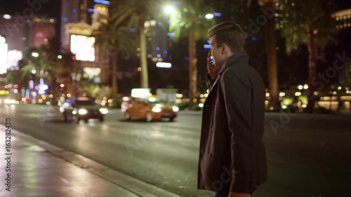 Young tourist is walking in Vegas at night and talking over his cellphone