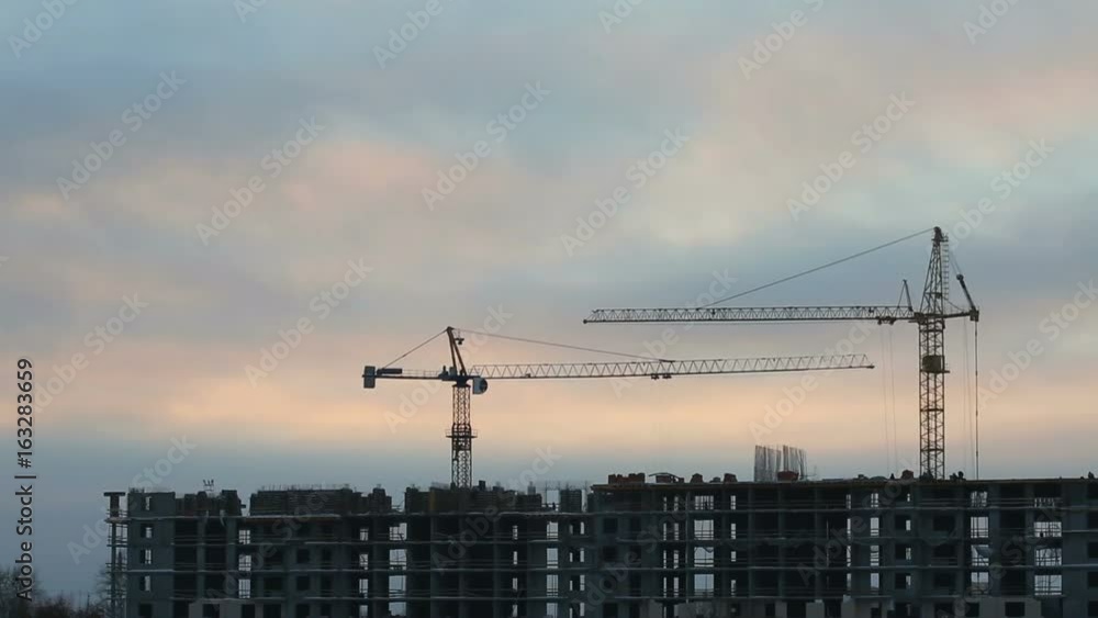 Construction site with working cranes at sunset Construction site with working cranes at sunset
