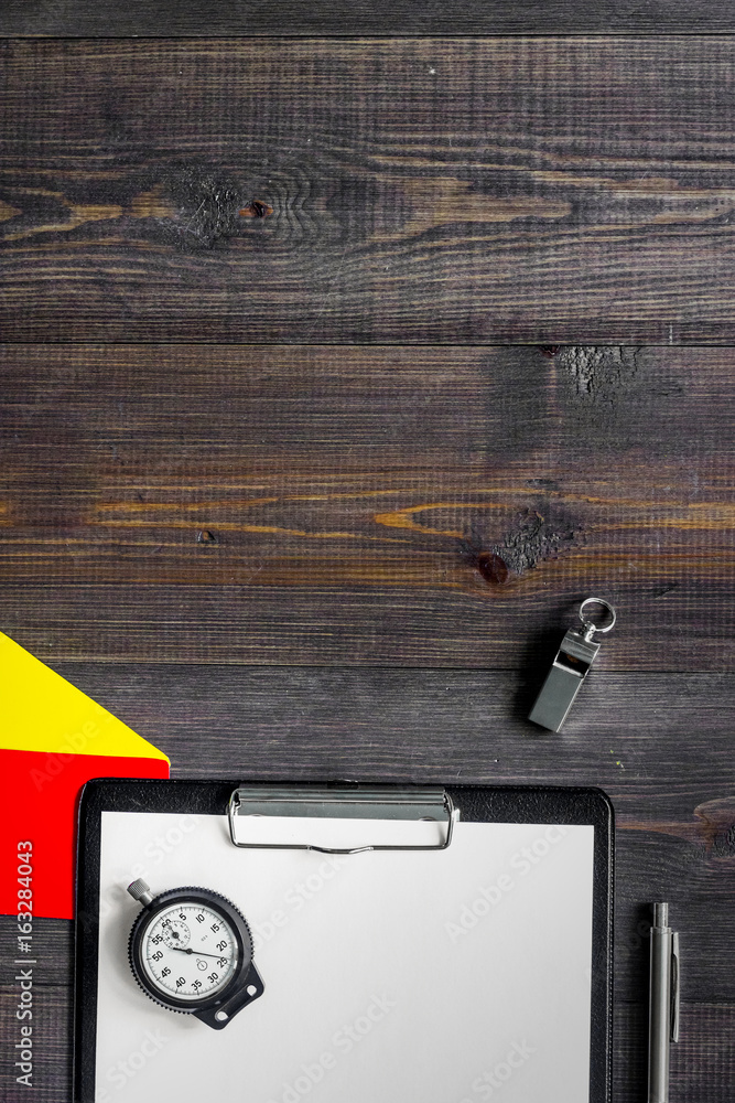 Referee tools. Yellow and red referee cards, whistle, stopwatch, pad, pen on wooden background top view copyspace Referee tools. Yellow and red referee cards, whistle, stopwatch, pad, pen on wooden background top view copyspace