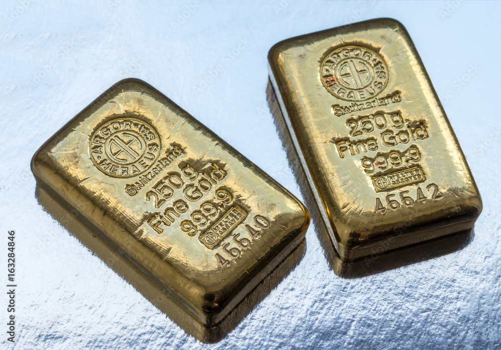 Two cast gold bars 250 grams on a light background.. Two cast gold bars 250 grams on a light background..
