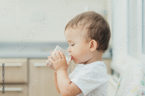 A boy drinks water in the kitchen