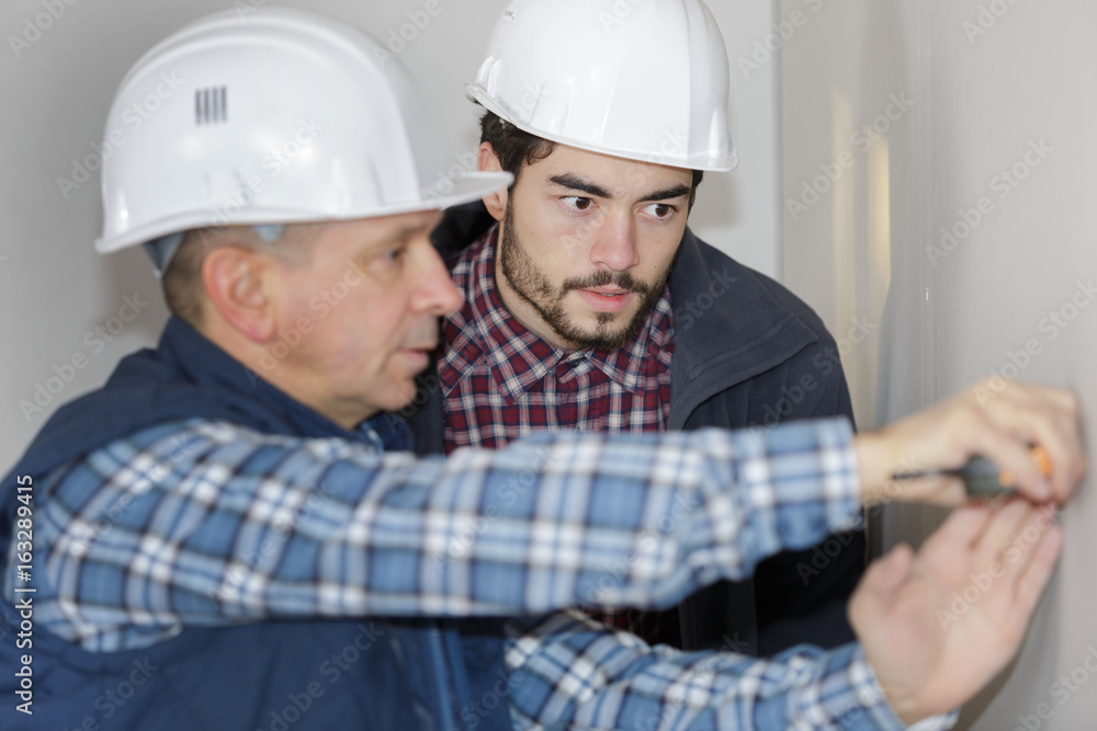 two electricians sockets installingat house construction site two electricians sockets installingat house construction site