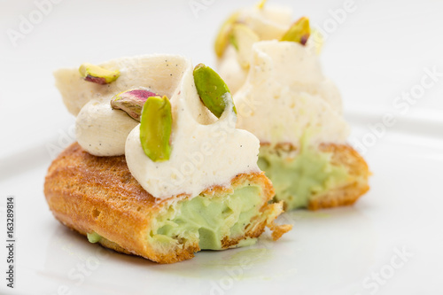 Cut eclair with vanilla cream and pistachio