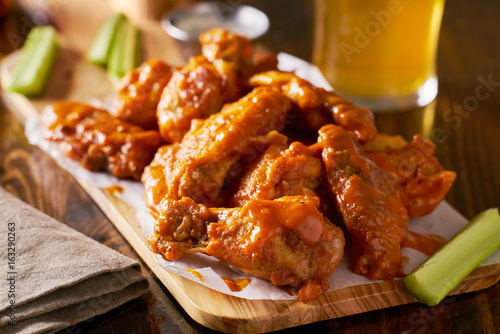 sauced buffalo chicken wings on wooden board with celery
