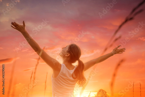 Free and happy woman against the sunset sky