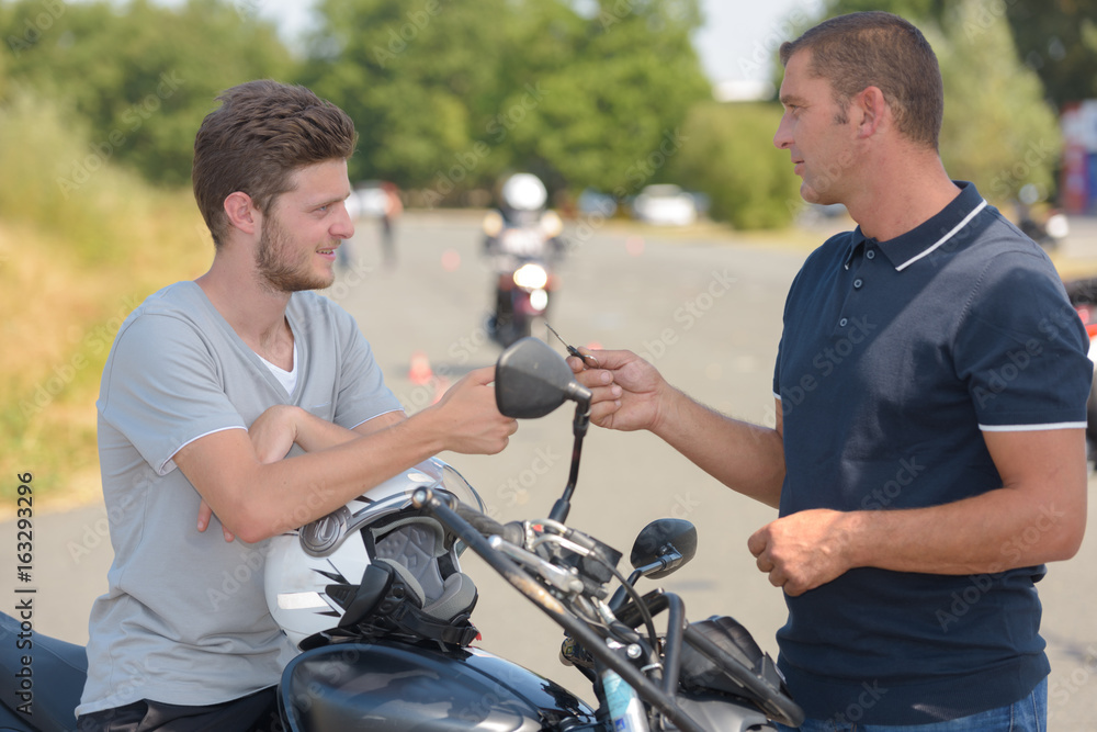 Man taking motorcycle training course talking to instructor