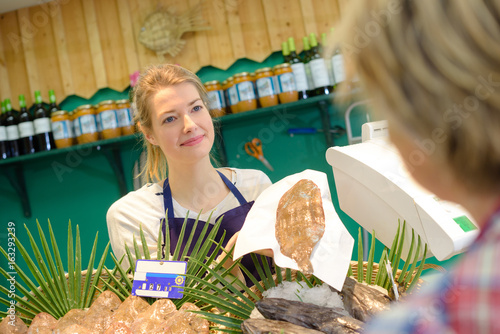 Fishmonger serving flatfish to customer photo