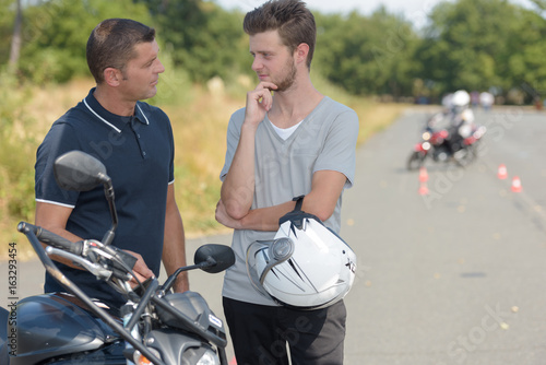 Bild auf Leinwand Young man talking to instructor of motorcycle training course