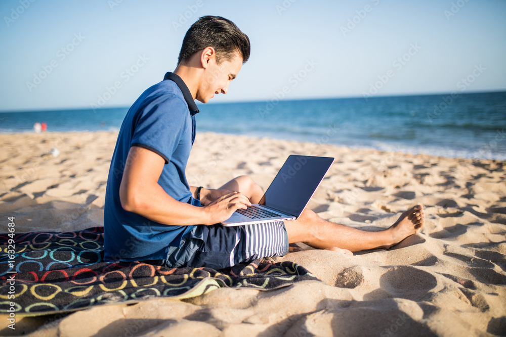 Young asian man working with laptop computer on tropical beach