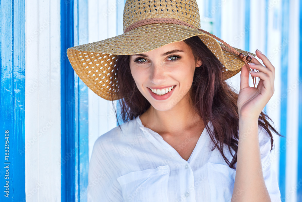 Portrait of a beautiful woman in a straw hat. Blue white background. sailor style