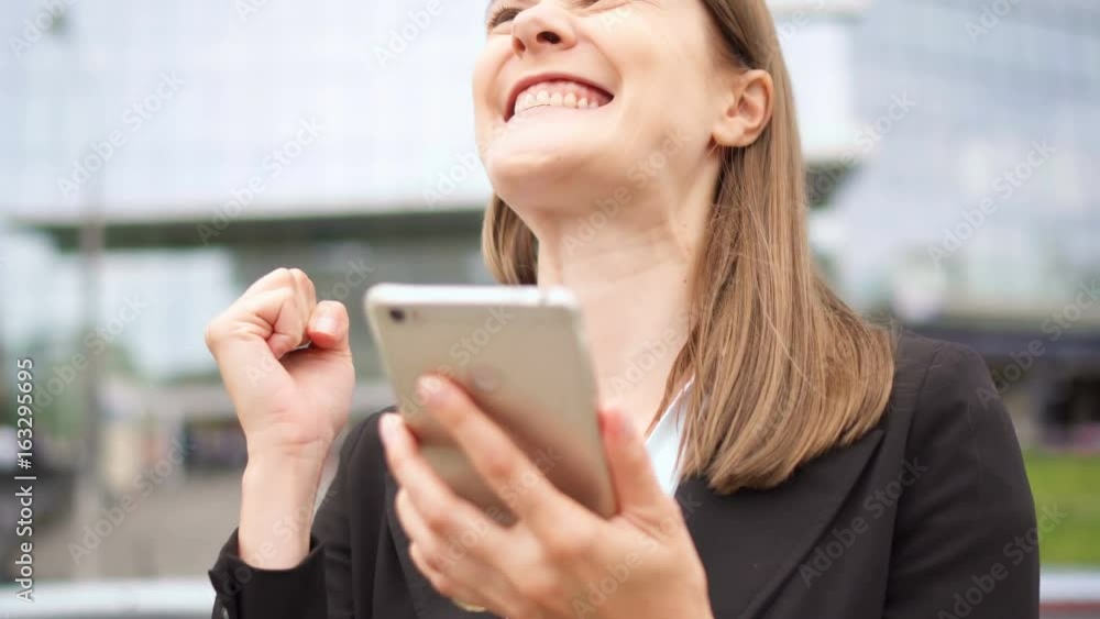 Businesswoman using smart phone in city downtown, professional female recieving good news excited Businesswoman using smart phone in city downtown, professional female recieving good news excited