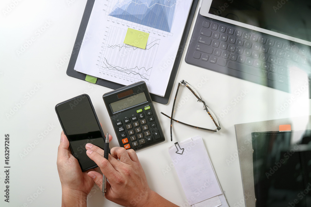 top view of businessman hand working with finances about cost and calculator and latop with mobile phone on withe desk in modern office top view of businessman hand working with finances about cost and calculator and latop with mobile phone on withe desk in modern office