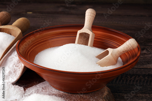 scoop with white sand and lump sugar on brown wooden background